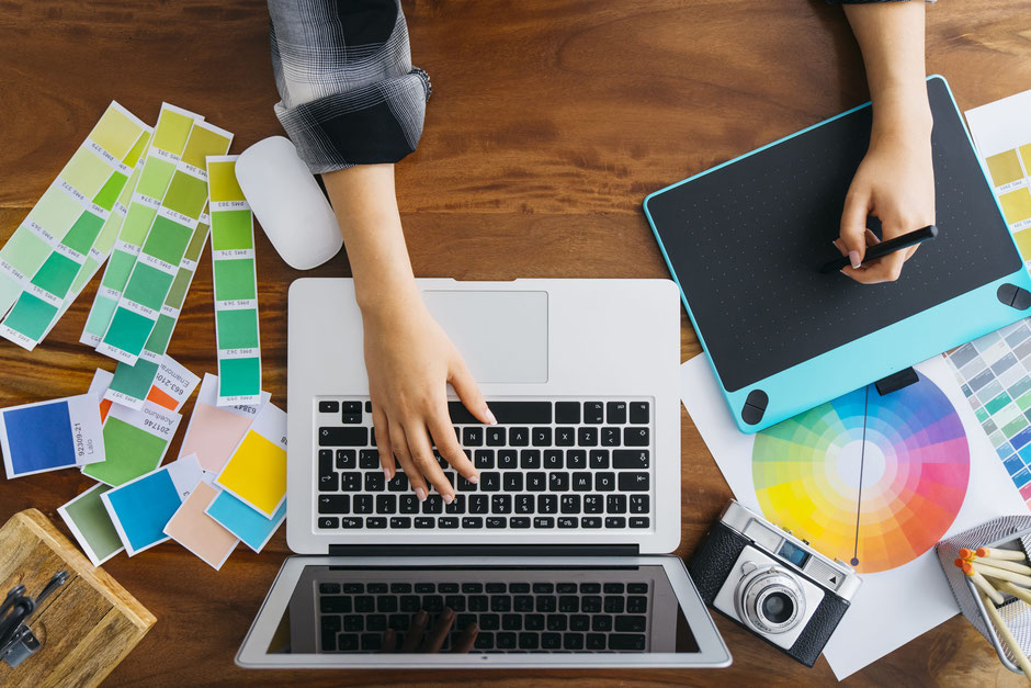 woman designing on computer with camera , colour cards and graphic design tablet